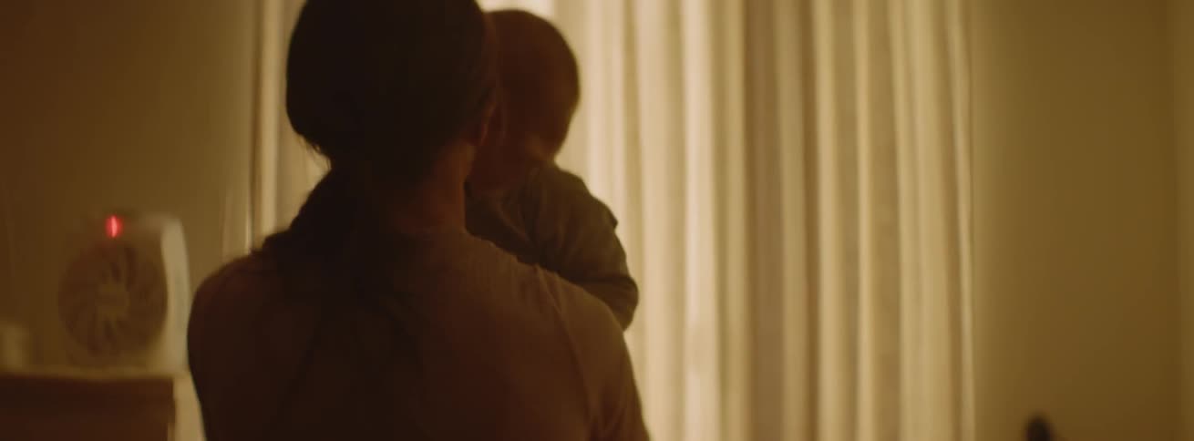 A mother is lifting her baby out of its crib inside in the morning