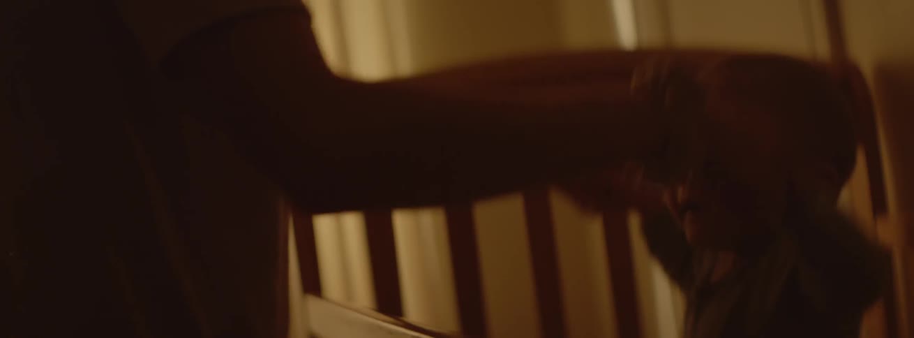A woman dances with a baby who is inside the crib