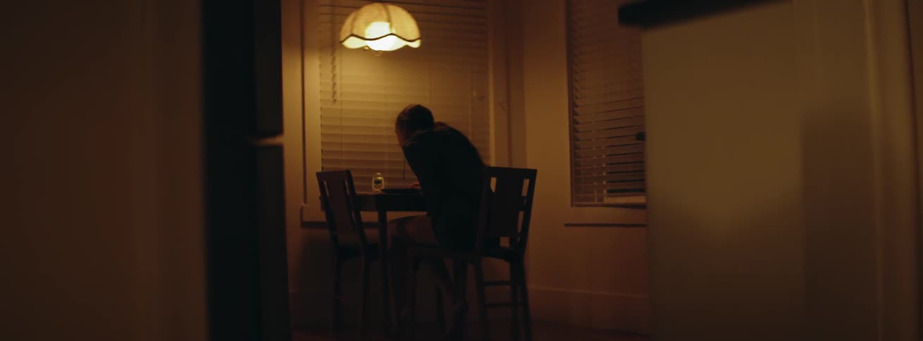 The woman sits at the table writing something