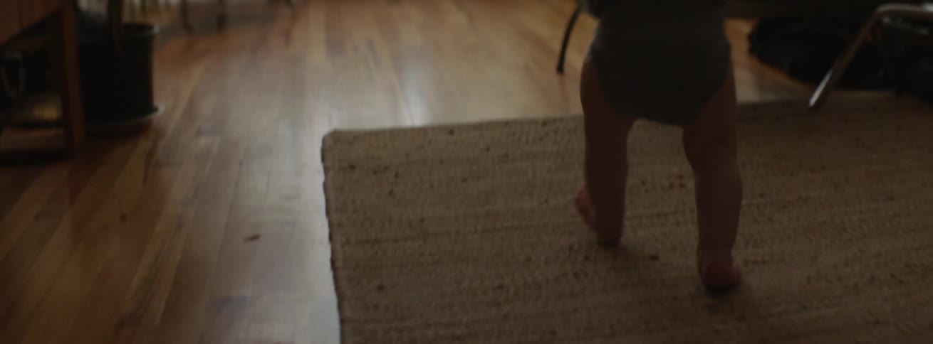 Toddler walks barefoot towards a water bottle on the floor