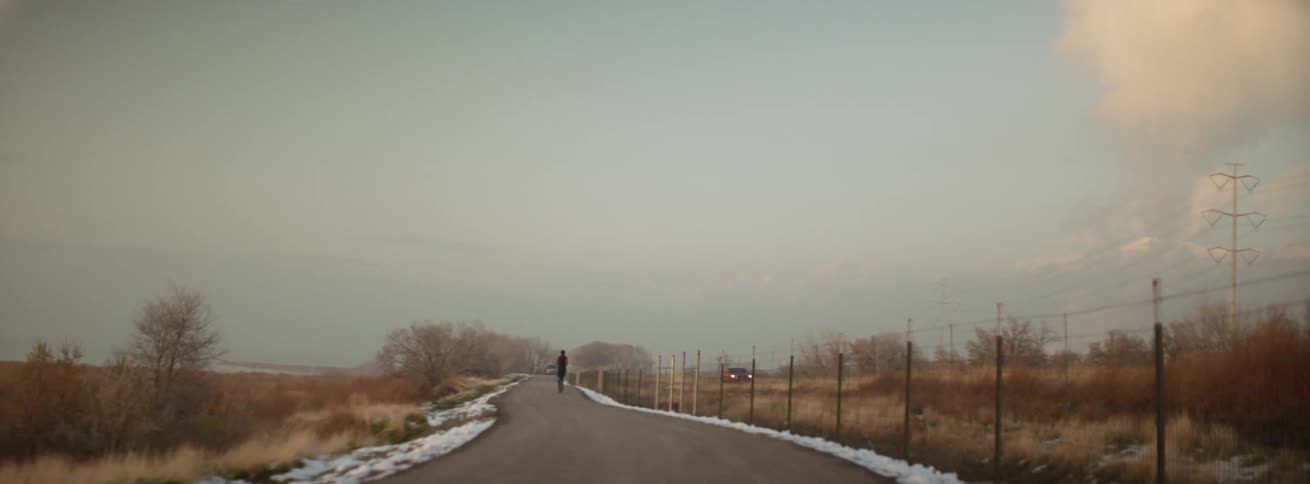 Man runs down a trail next to a highway