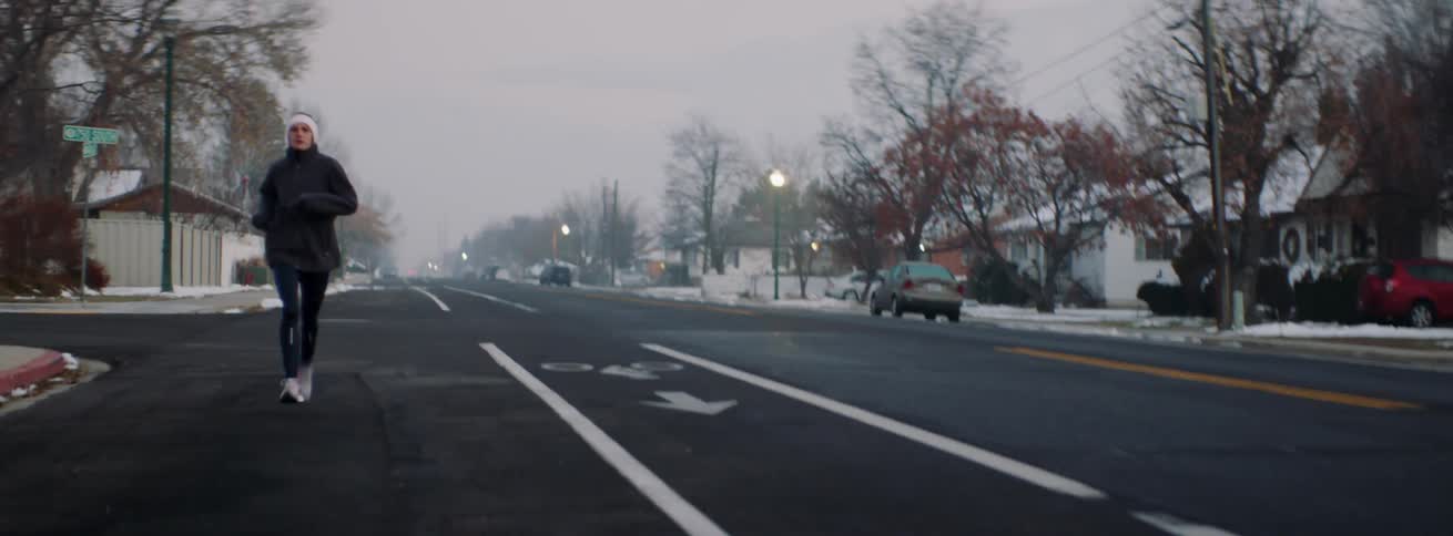 Woman jogs on a street at sunset