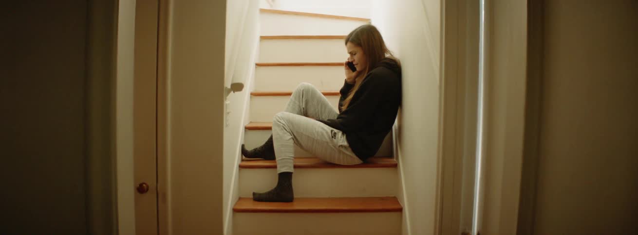 A girl sits on the steps talking on her phone