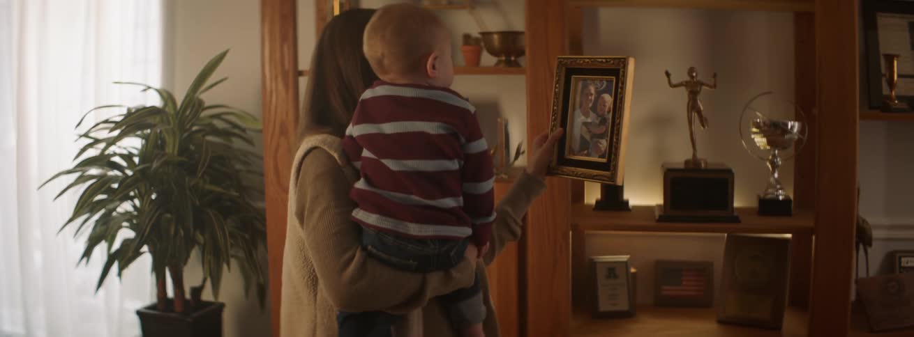 A mother and baby look at a framed photograph