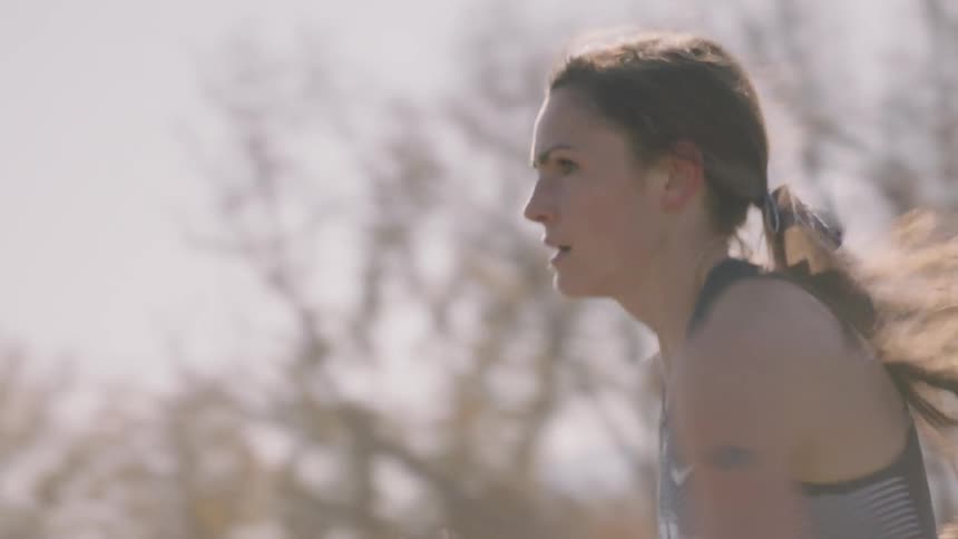 A woman is running fast outside on a track