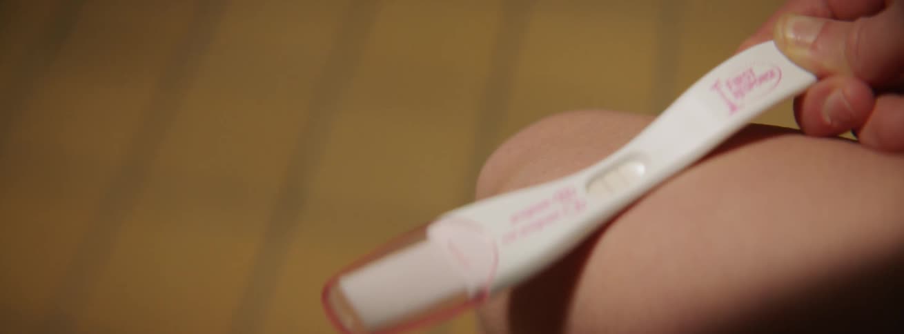 A woman watches a pregnancy test