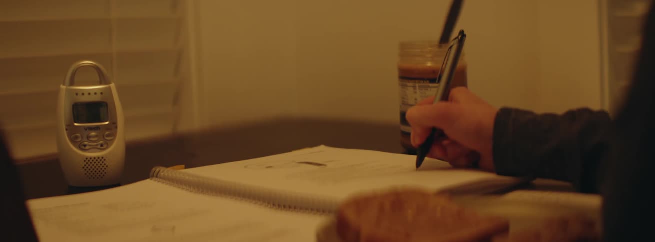Woman writes in a notebook while eating a peanut butter sandwich