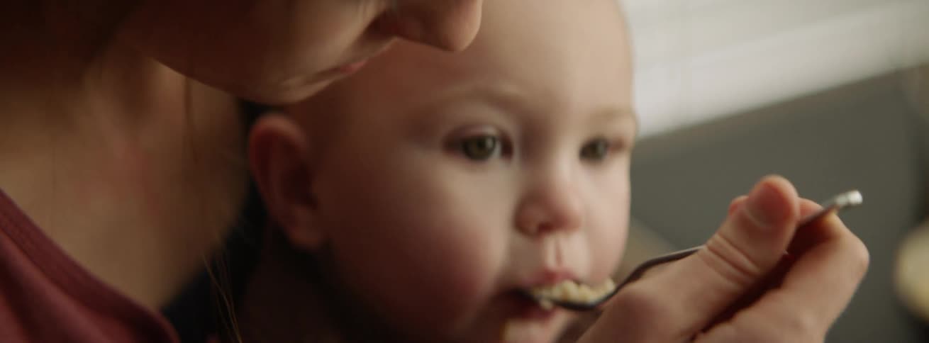 The baby is being fed by spoon