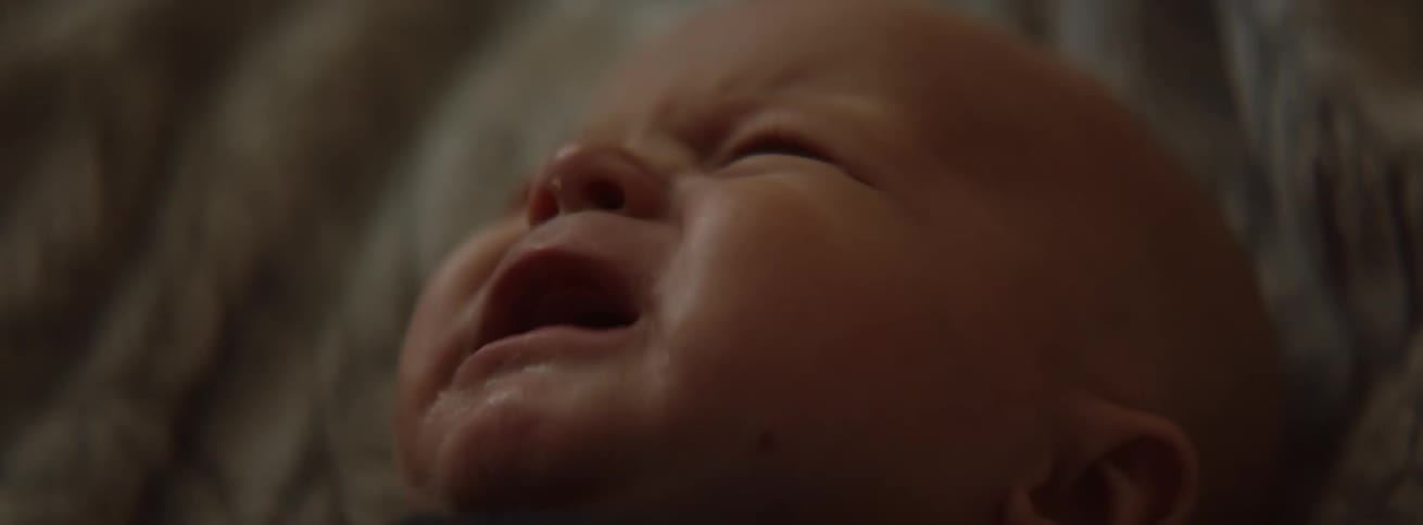 A baby is crying as it is lying down inside in daylight
