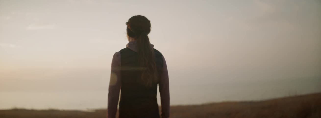 A woman is stopping to watch the sunrise in a natural setting