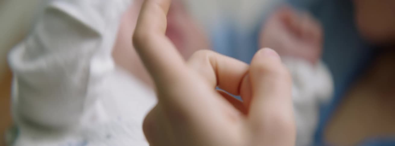 The baby grabs the person's finger