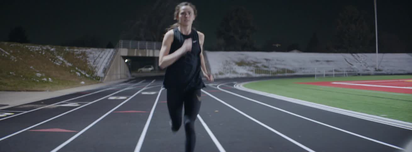 A woman races off on the track at night