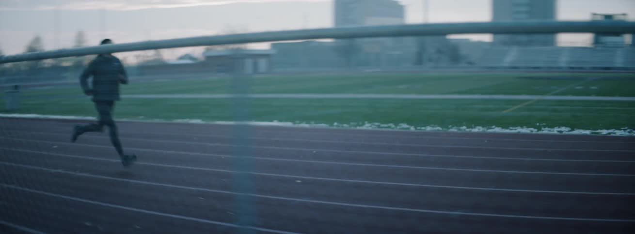 Woman runs on an outdoor track at sunset