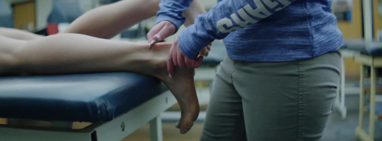 A trainer massages the back of an athletes leg