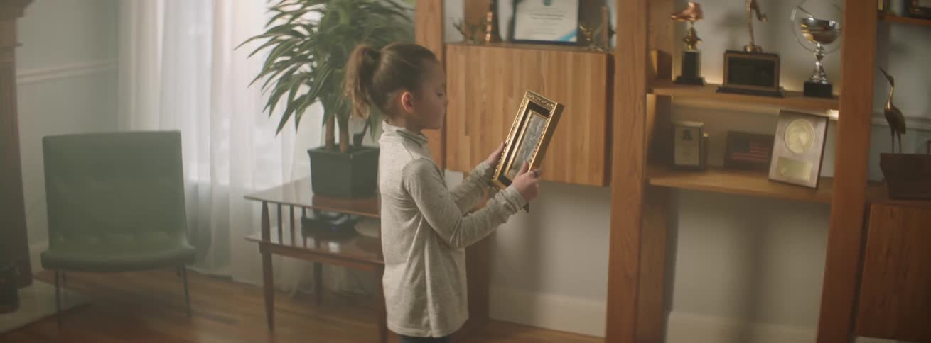 A child is holding a framed photograph in her hands