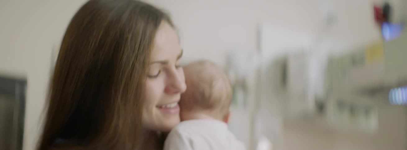 A woman smiles as she rocks her baby in her arms
