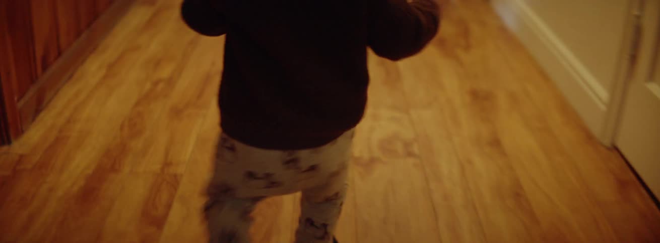 A baby walks on a wooden floor