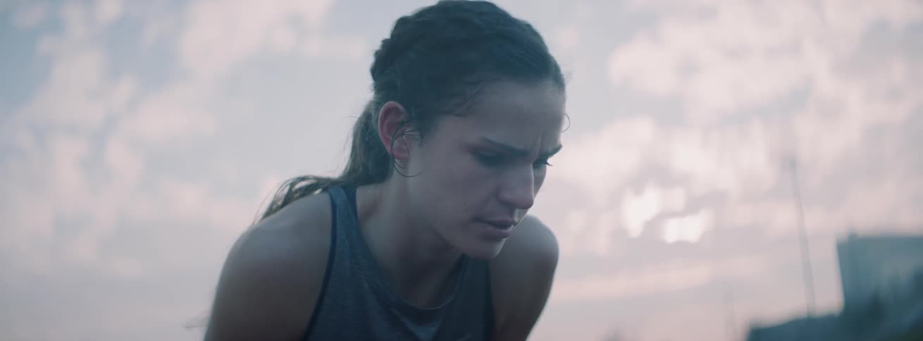 A runner leans over to catch her breath at sunset