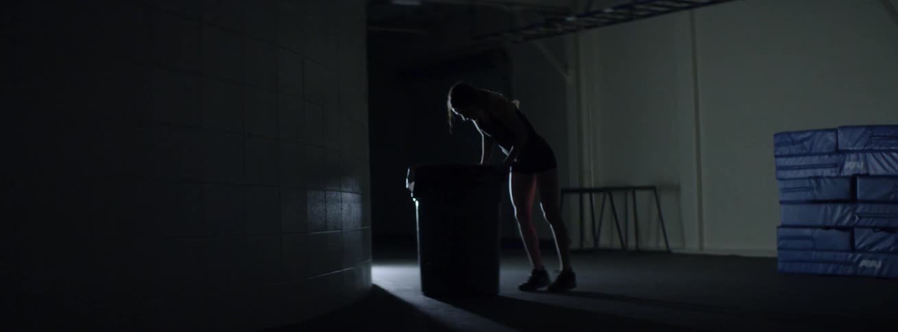 Woman vomits into a trashcan