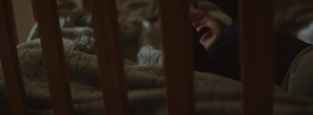 Baby lays in his crib as he clasps his hands
