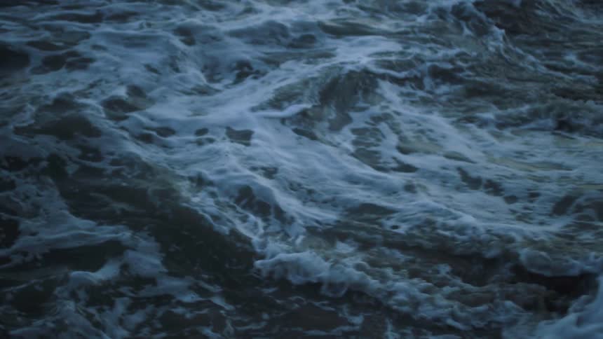 The ocean tide is receding from a beach at dusk