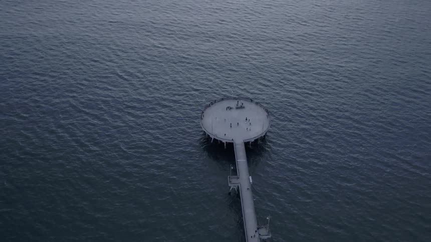 People are visiting a pier on the coast at dusk