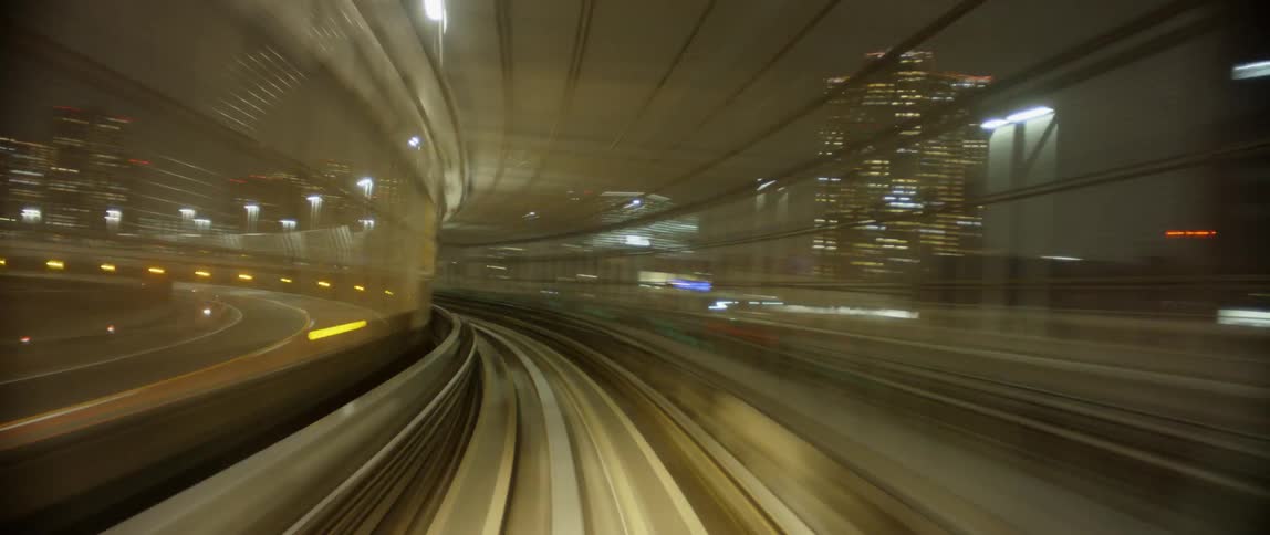 A commuter train is traveling on an elevated track in a city at night