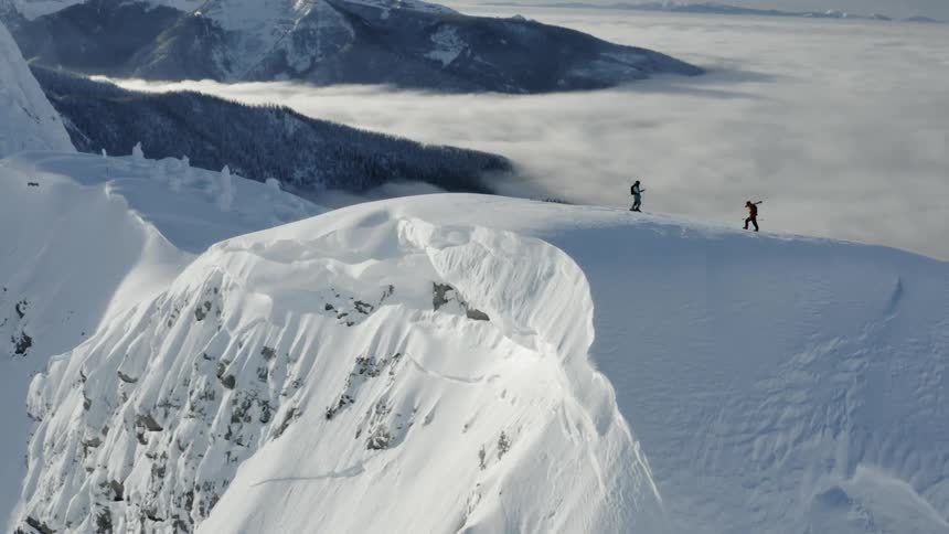 Two people high on a snowy peak on a cloudy day