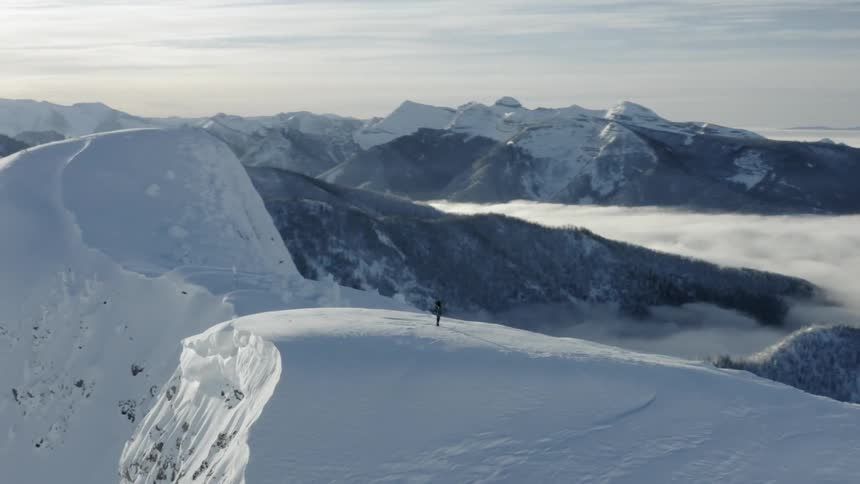 A person is standing on the snow covered mountain top