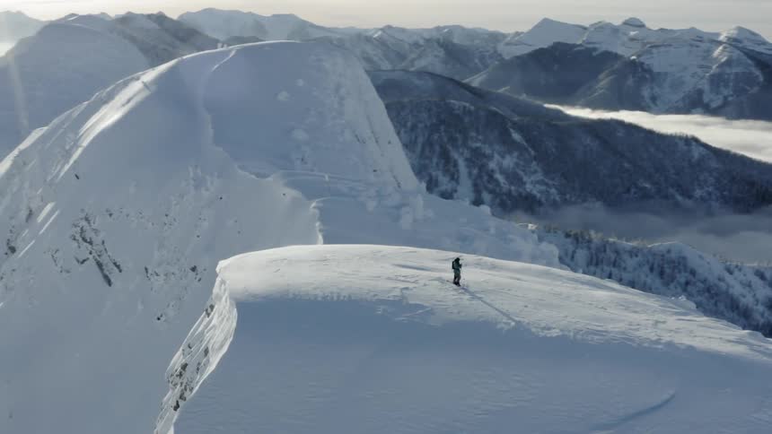 A man stands atop a snowy mountain
