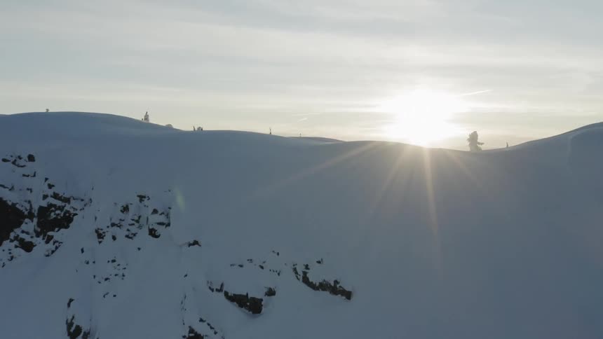 The sun is shining on the horizon beyond a mountain ridge