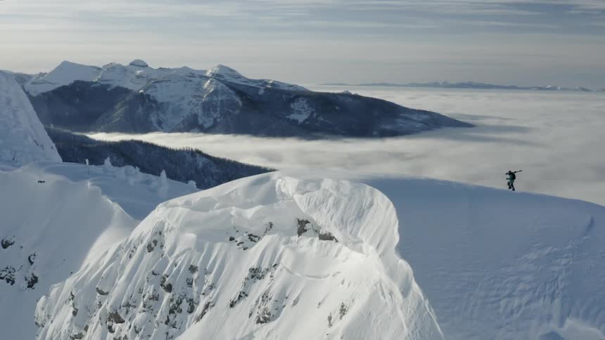 The person is hiking towards the edge of the snow covered mountain