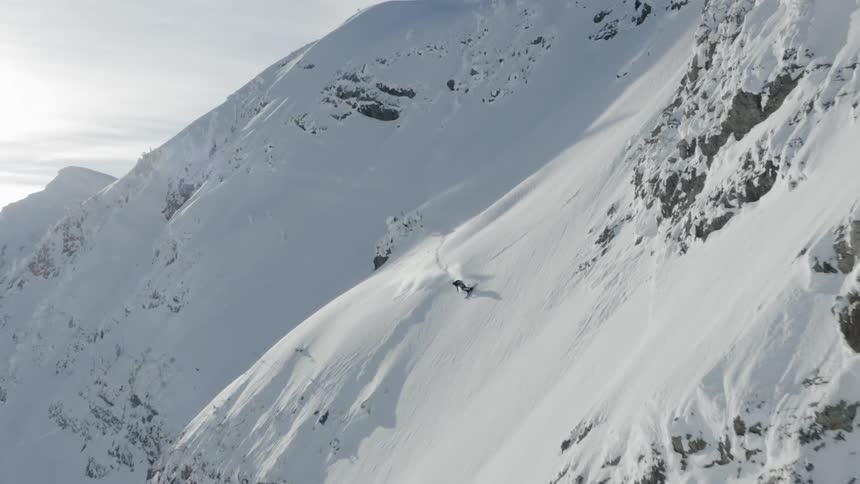 A skier is skiing down a mountain slope during the day