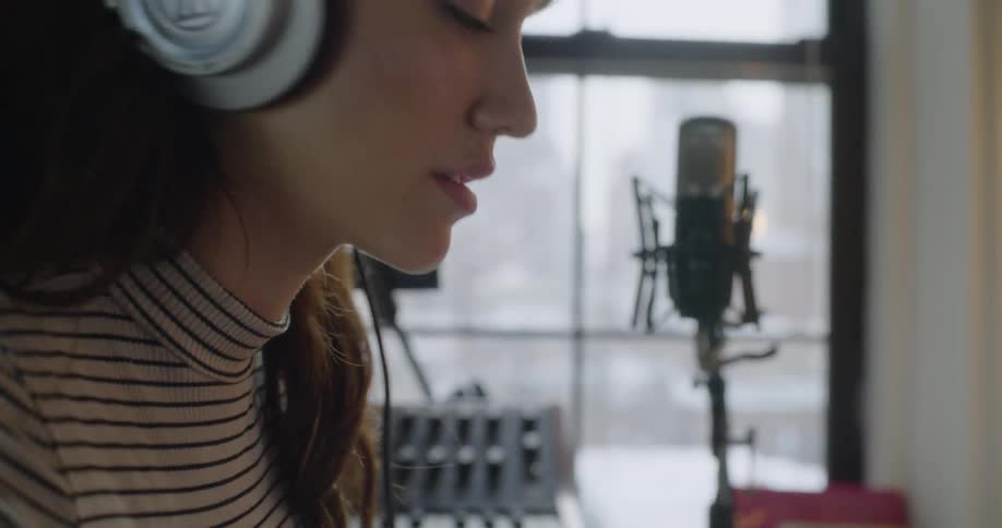 Woman swaying to music while wearing headphones in a recording area