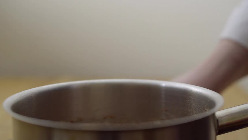 Person pours items into a pot and uses a whisk to mix it