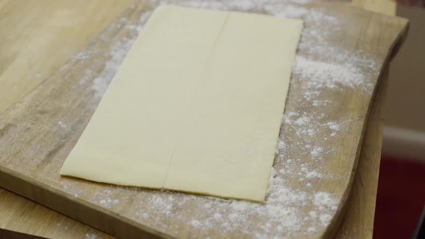 Cooking board being covered with a pastry and cut up
