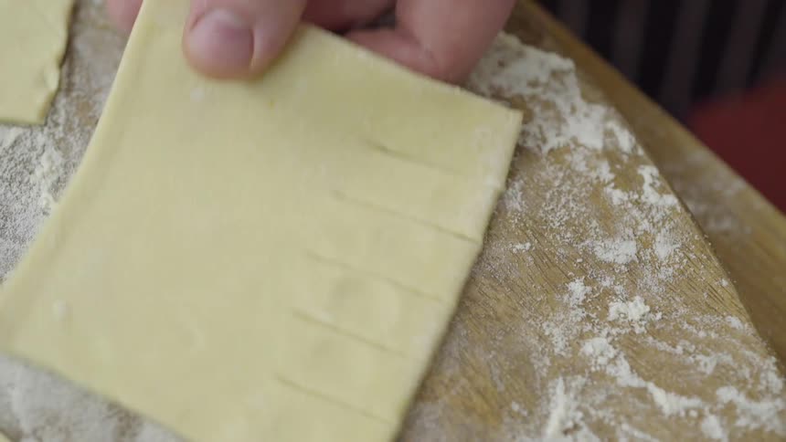 A person uses a knife to notch dough