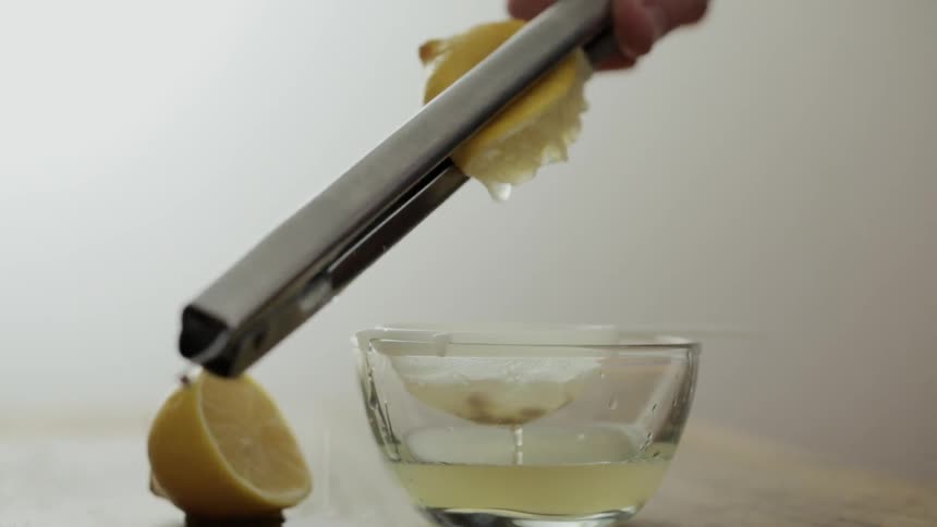 Someone is using tongs to squeeze juice from lemons