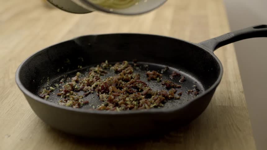 Person pours pasta into an iron pan