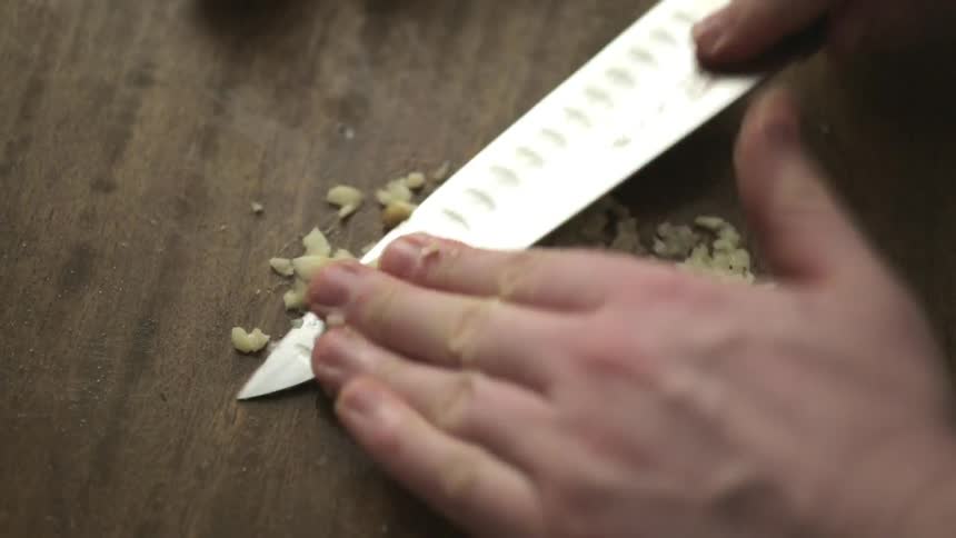 Person chopping garlic with a knife
