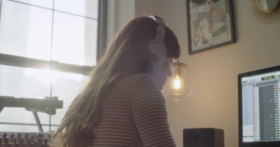 A woman is wearing headphones in front of the computer