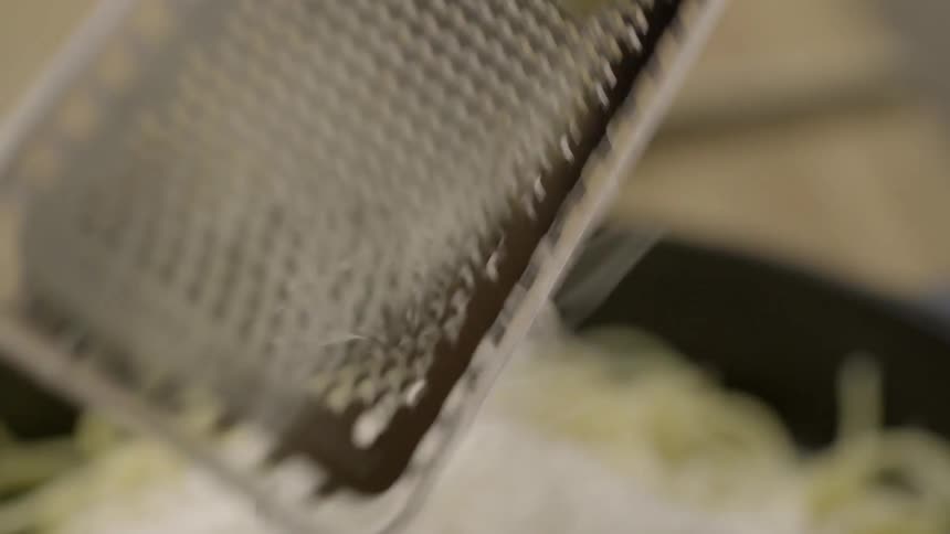 Person grating cheese on some pasta