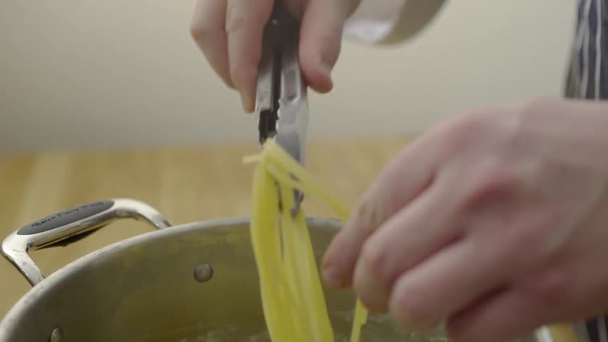 Spaghetti being pulled out of boiling water