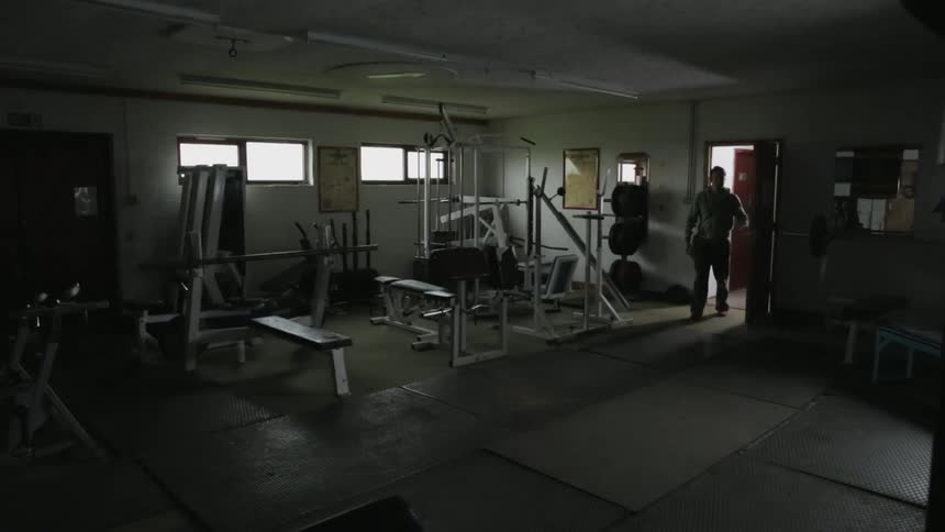 A man walks into a dark gym