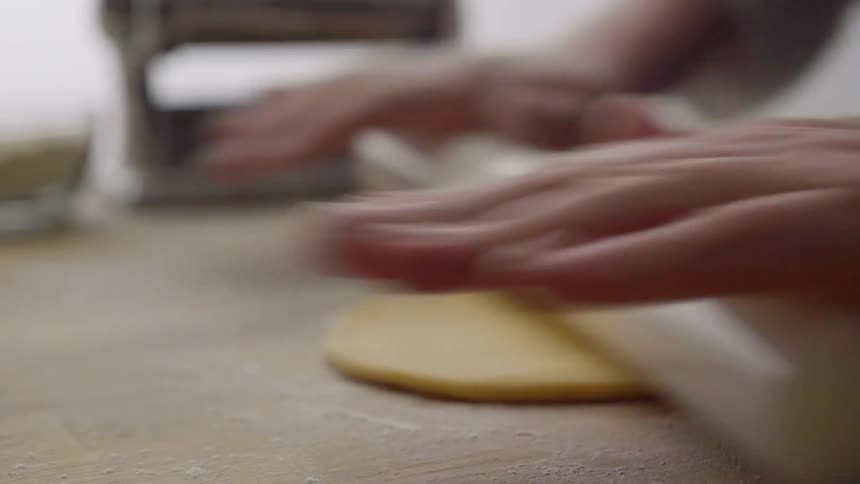 Close up of person rolling dough with a rolling pin