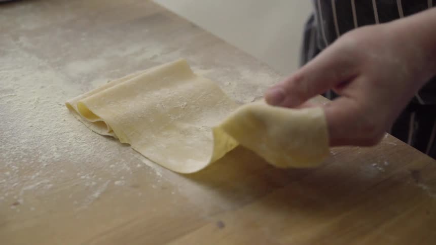 A man folds dough on a floured surface