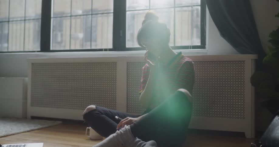 Woman talks on the phone while sitting on the floor