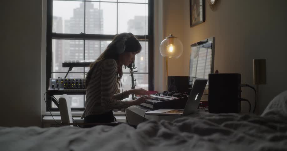 Woman plays a keyboard in an apartment bedroom