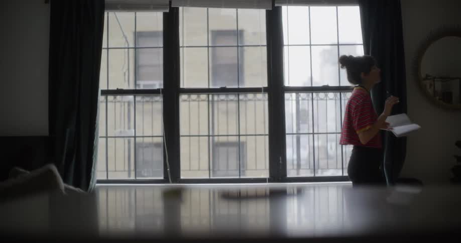 Woman reading and pacing back and forth in a large room in a city