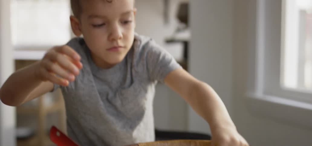 A child is putting cheese on a salad